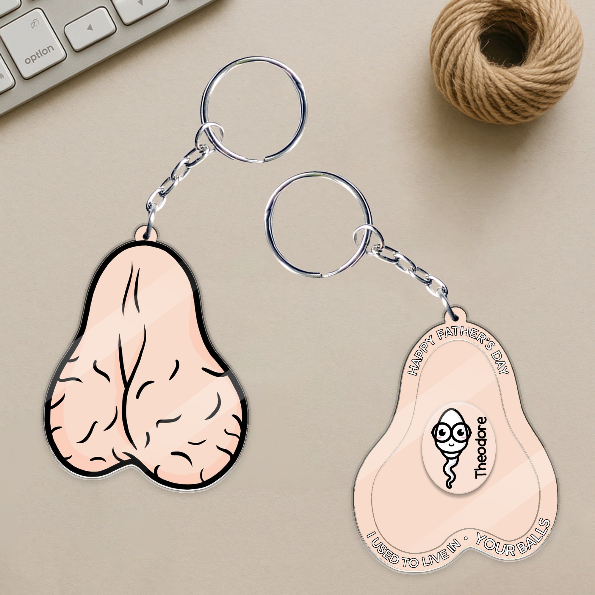 Personalized Father’s Day shaker keychain on desk, acrylic keychain showing front and back with custom sperm illustration