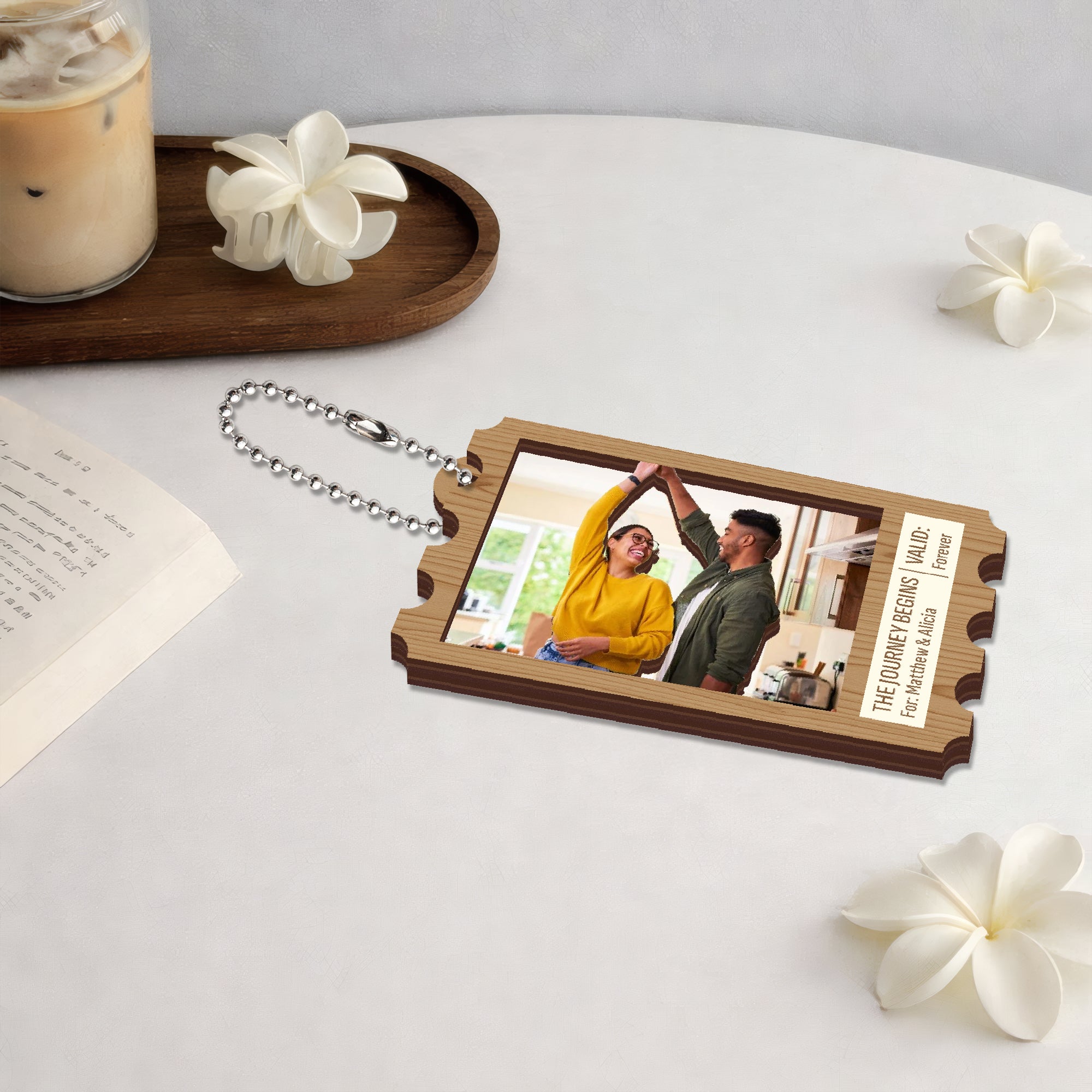 Custom wooden keychain with couple photo displayed on desk with coffee and decorative flowers